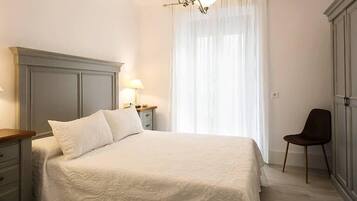 A bedroom with a bed, a nightstand, a chair, and a wardrobe.