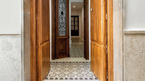 Un pasillo con puertas de madera y un suelo con diseño.
