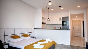 Habitación de hotel moderna con cama, escritorio, kitchenette y baño.