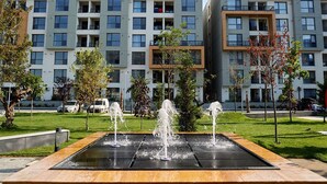 Un moderno edificio de apartamentos con varios balcones y un patio central con fuente de agua.