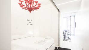 A modern bedroom with a bed, a chandelier, a wall with a motivational quote, and a view of a balcony with outdoor furniture. - Hemeras Boutique House Aparthotel Duomo 11 (Milan)