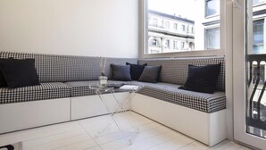 A corner seating area with a houndstooth patterned sofa, black cushions, and a clear glass coffee table. - Hemeras Boutique House Aparthotel Duomo 11 (Milan)