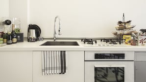 A modern kitchen with a stainless steel sink, a coffee maker, and a range of kitchen appliances including a microwave and oven. - Hemeras Boutique House Aparthotel Duomo 11 (Milan)