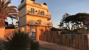 Un hotel de diseño moderno, con fachada curva, varios balcones y un cerramiento de madera alrededor de la propiedad.