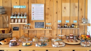 Mostrador de panadería con diversos productos horneados, frascos de conservas y una pizarra.