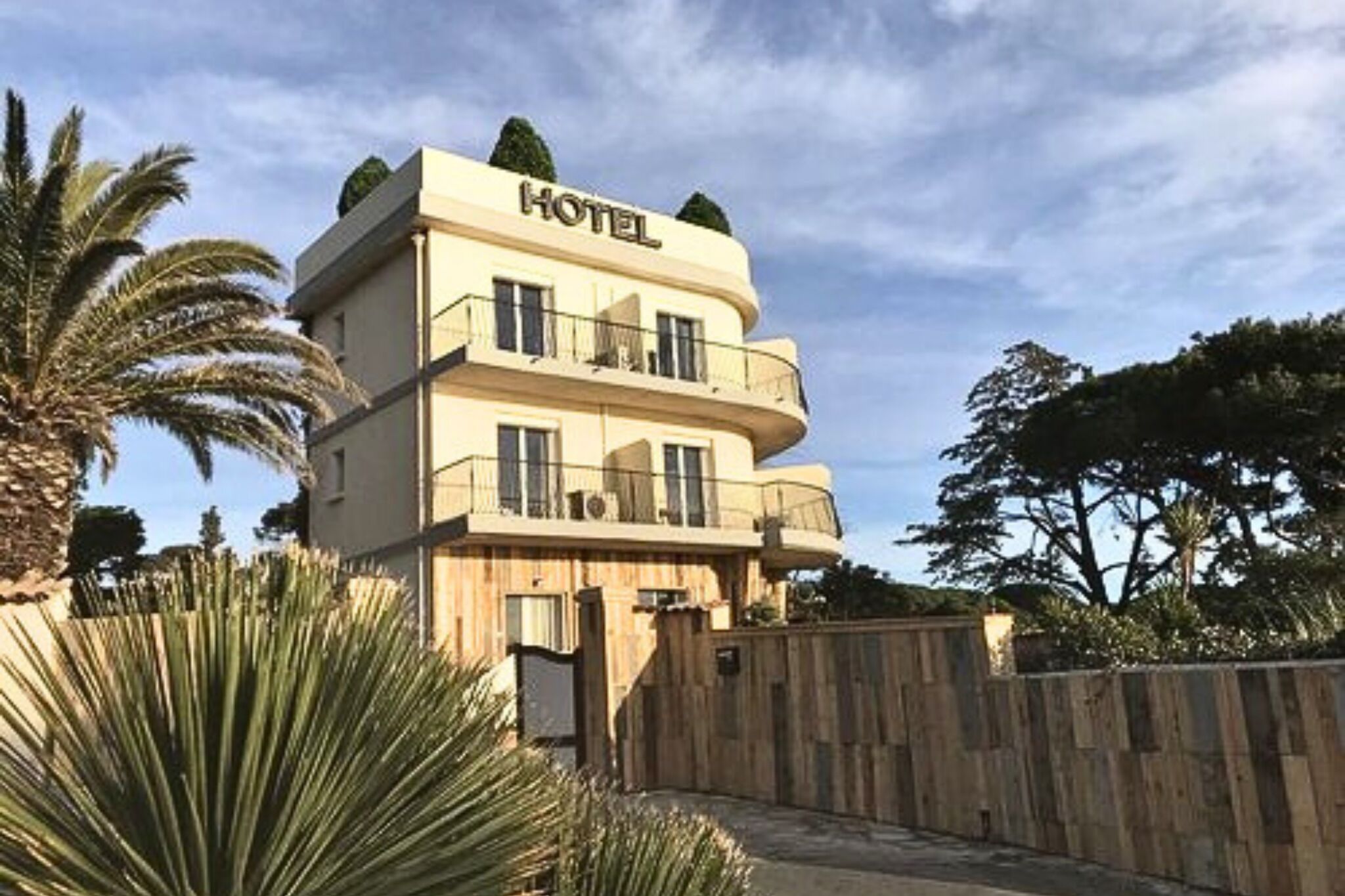 A hotel with a two-story structure, balconies, and a wooden fence in the foreground.