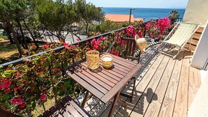 Una terraza de madera con una mesa y sillas, con vista a una playa y el océano.