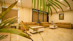 A modern living room with a beige sofa set, a coffee table, and a potted plant. - Hotel Aarunya Royale (Luni)
