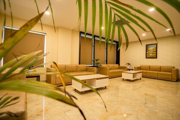Una sala de estar moderna con un sofá color beige, una mesita de centro y una planta en maceta.