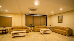 A spacious living room with a beige sofa set, a coffee table, and a potted plant. - Hotel Aarunya Royale (Luni)