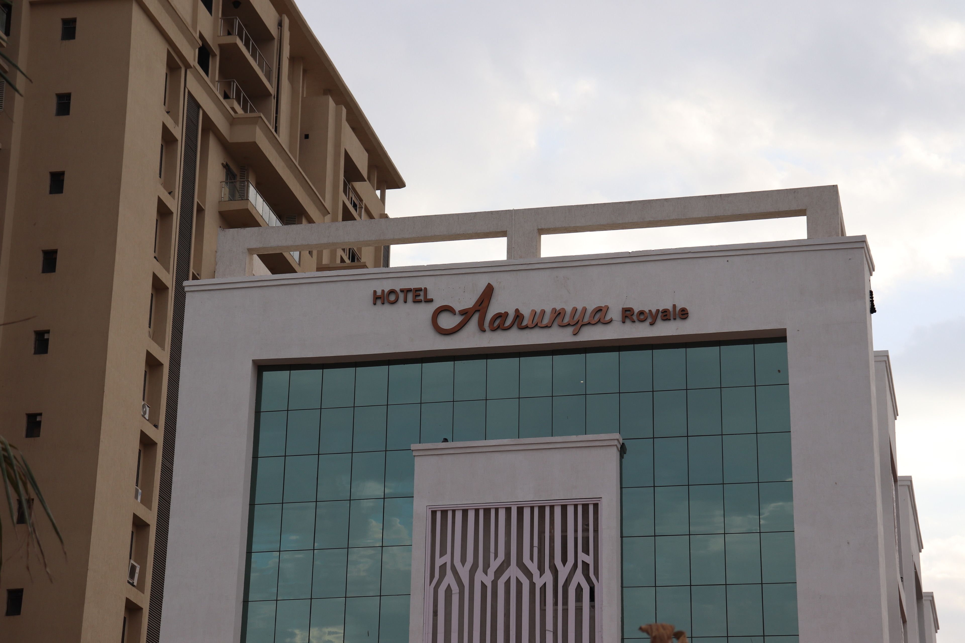 Um edifício de hotel com a inscrição em destaque na fachada: Hotel Arjuna Royale.