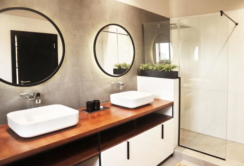 Ein modernes Badezimmer mit zwei Waschbecken, einem großen Spiegel und einer Duschkabine.