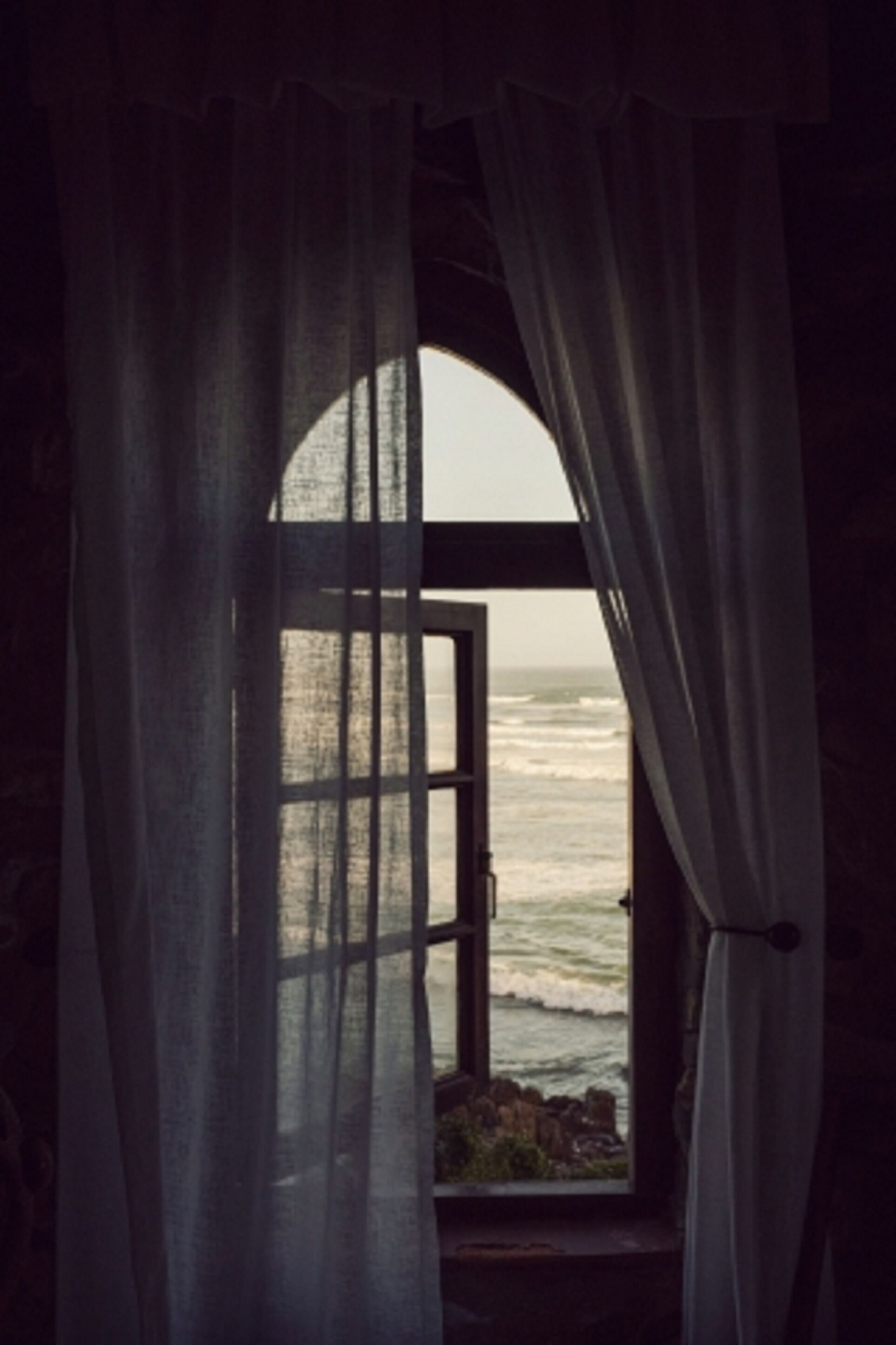 Un arco de entrada con vistas al océano a través de cortinas traslúcidas.