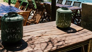 A wooden deck with tables and chairs, overlooking a beach with waves. - Buccara Noetzie - Lindsay Castle (Knysna)