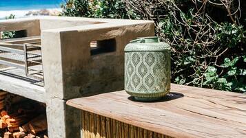 A concrete bench with a metal railing, a green patterned lantern, and a wooden table.