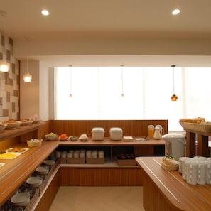 Disposición de bufé con diversos alimentos y recipientes, una ventana con luz natural y una encimera de madera.