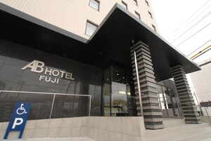 Entrada de hotel com um letreiro indicando 'AB HOTEL FUJI' e sinal de vaga para estacionamento de deficientes.