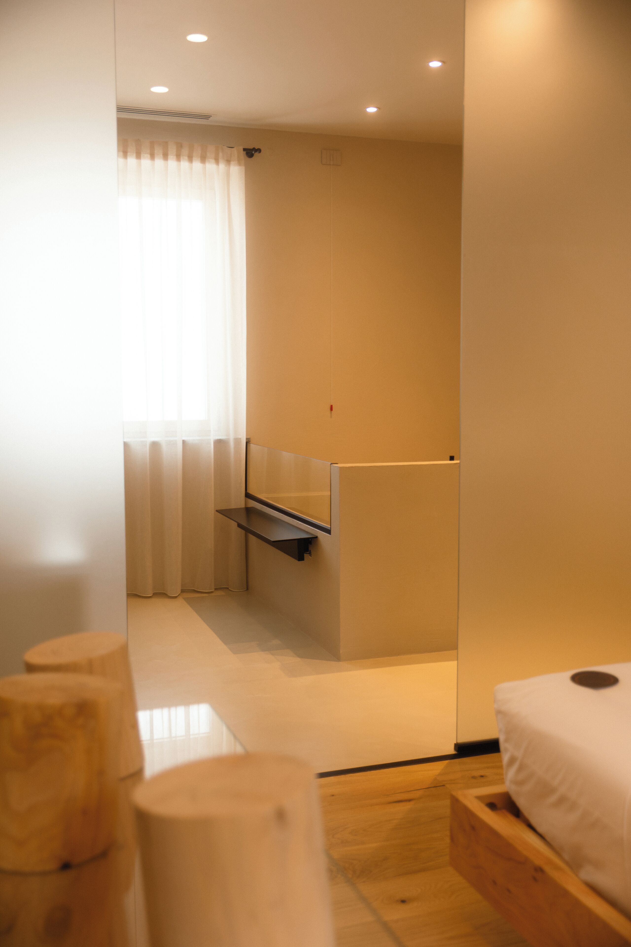 A modern bedroom with a wooden bed frame, a small bedside table, and a built-in bench.