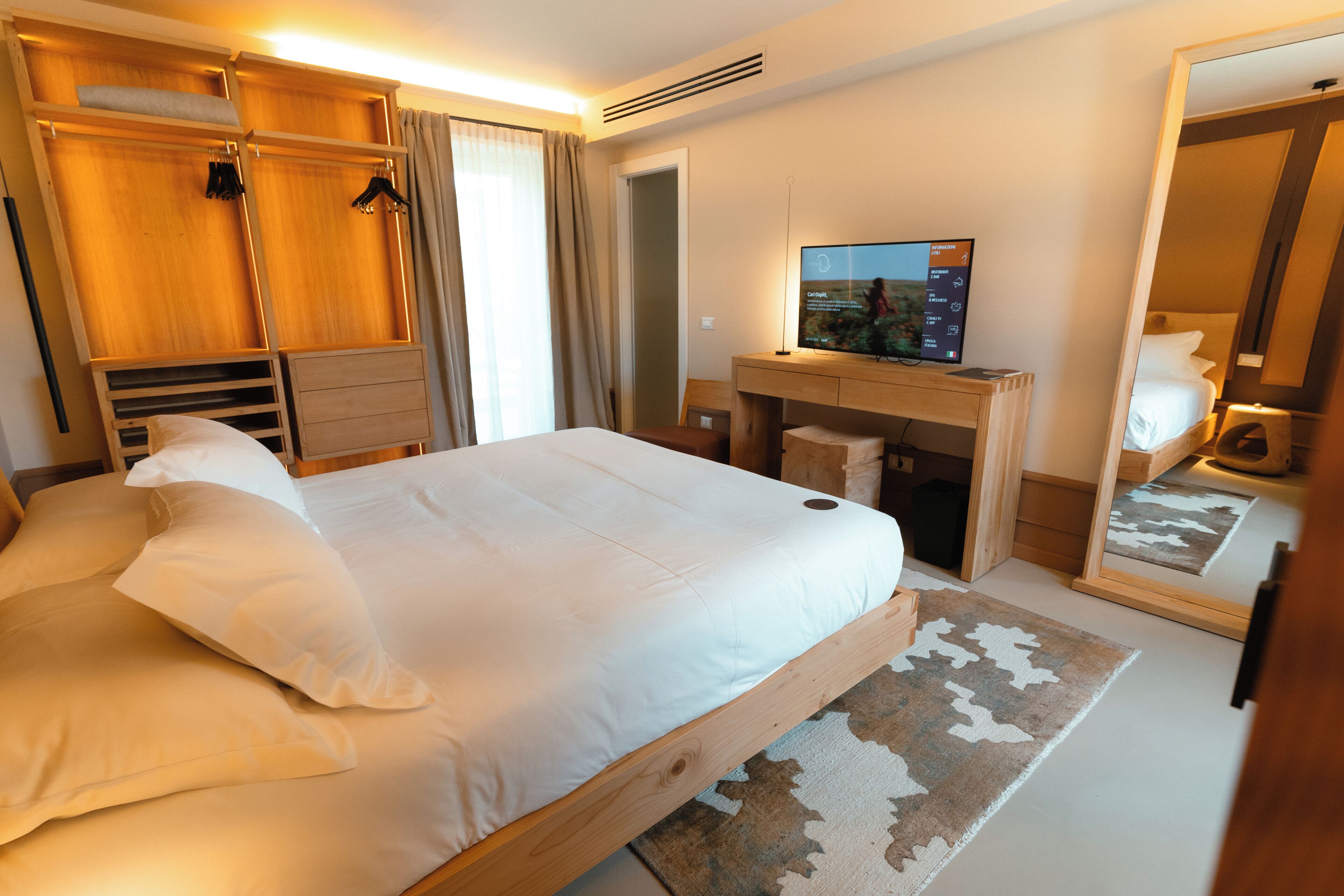 Une chambre d’hôtel avec un grand lit, une armoire en bois, un bureau et un téléviseur.