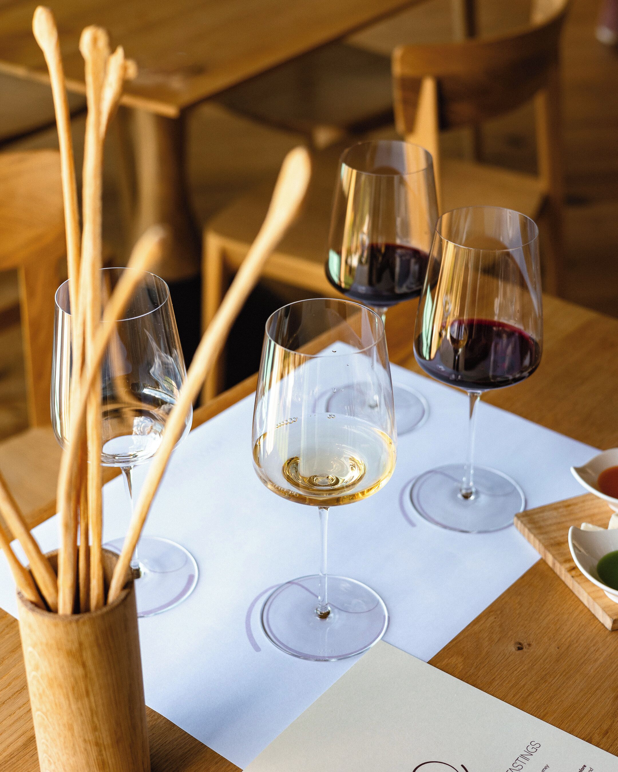 A table with wine glasses and wooden utensils, suggesting a dining setting.