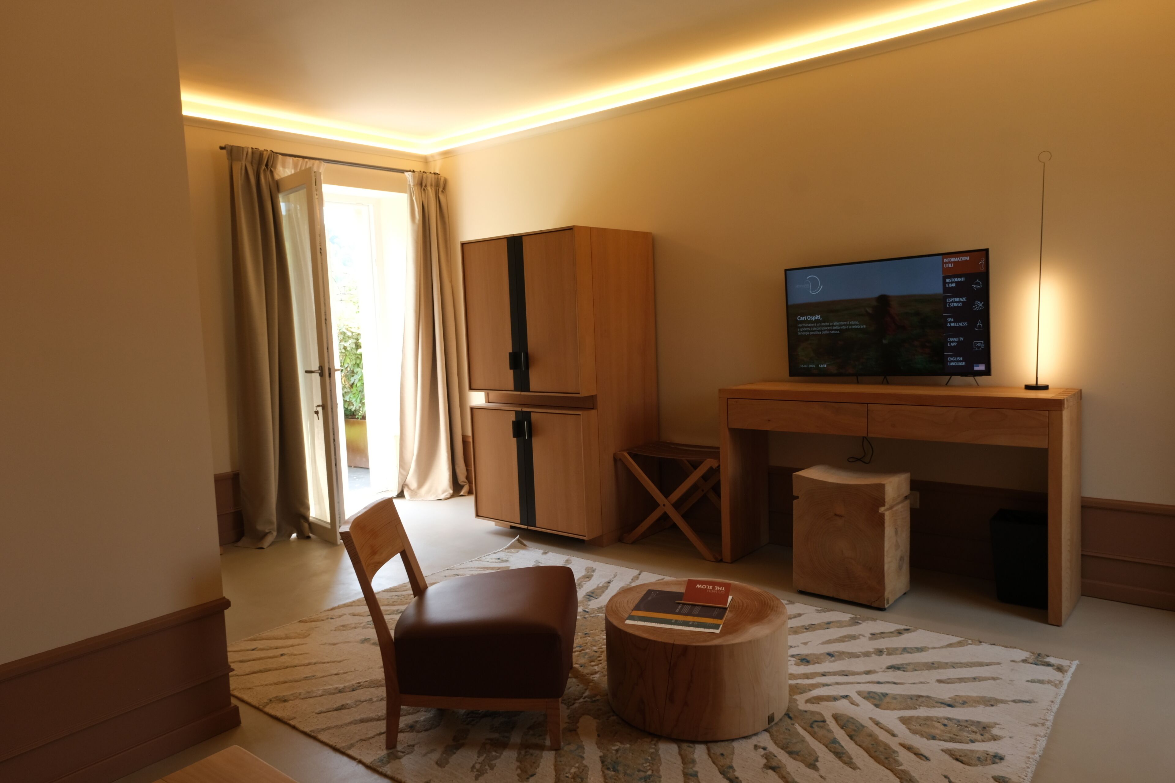A modern living room with a wooden cabinet, a television, a chair, and a small table.