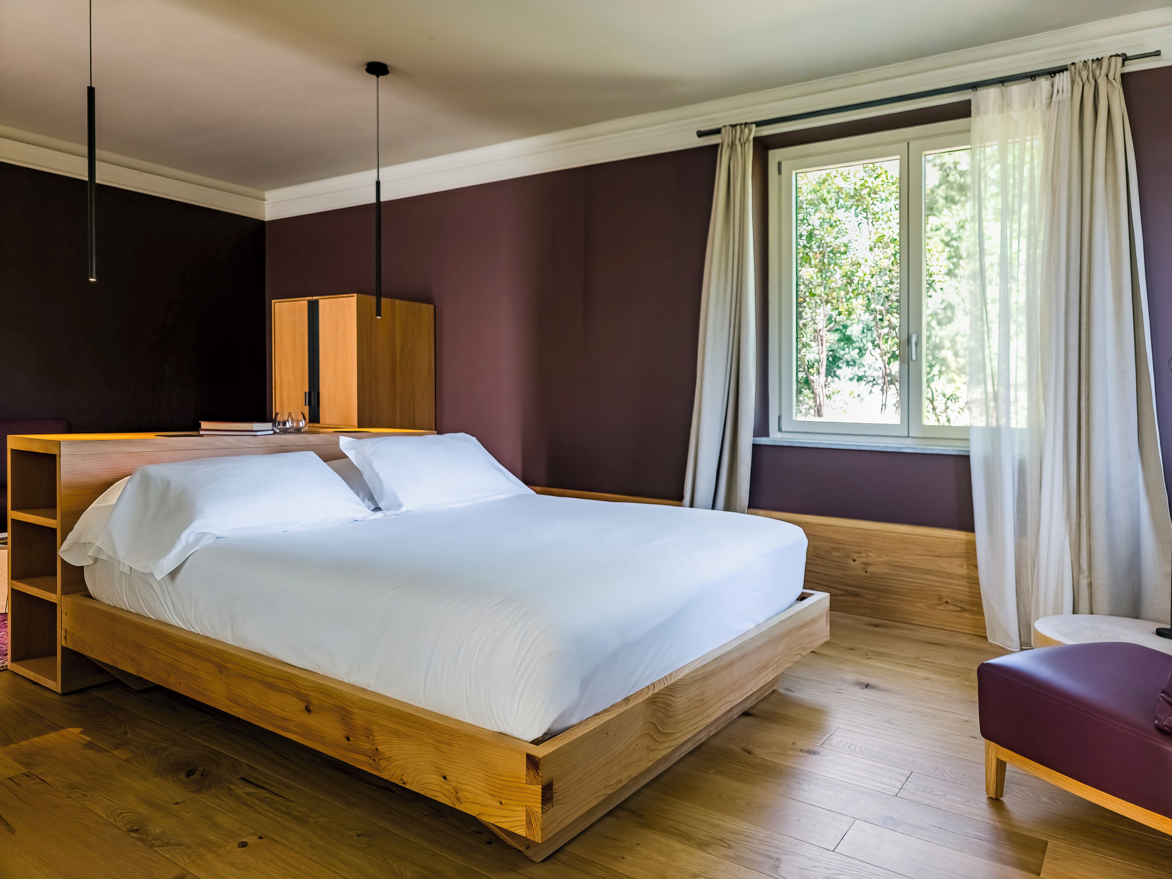 A modern bedroom with a wooden bed, a wardrobe, and a window with curtains.