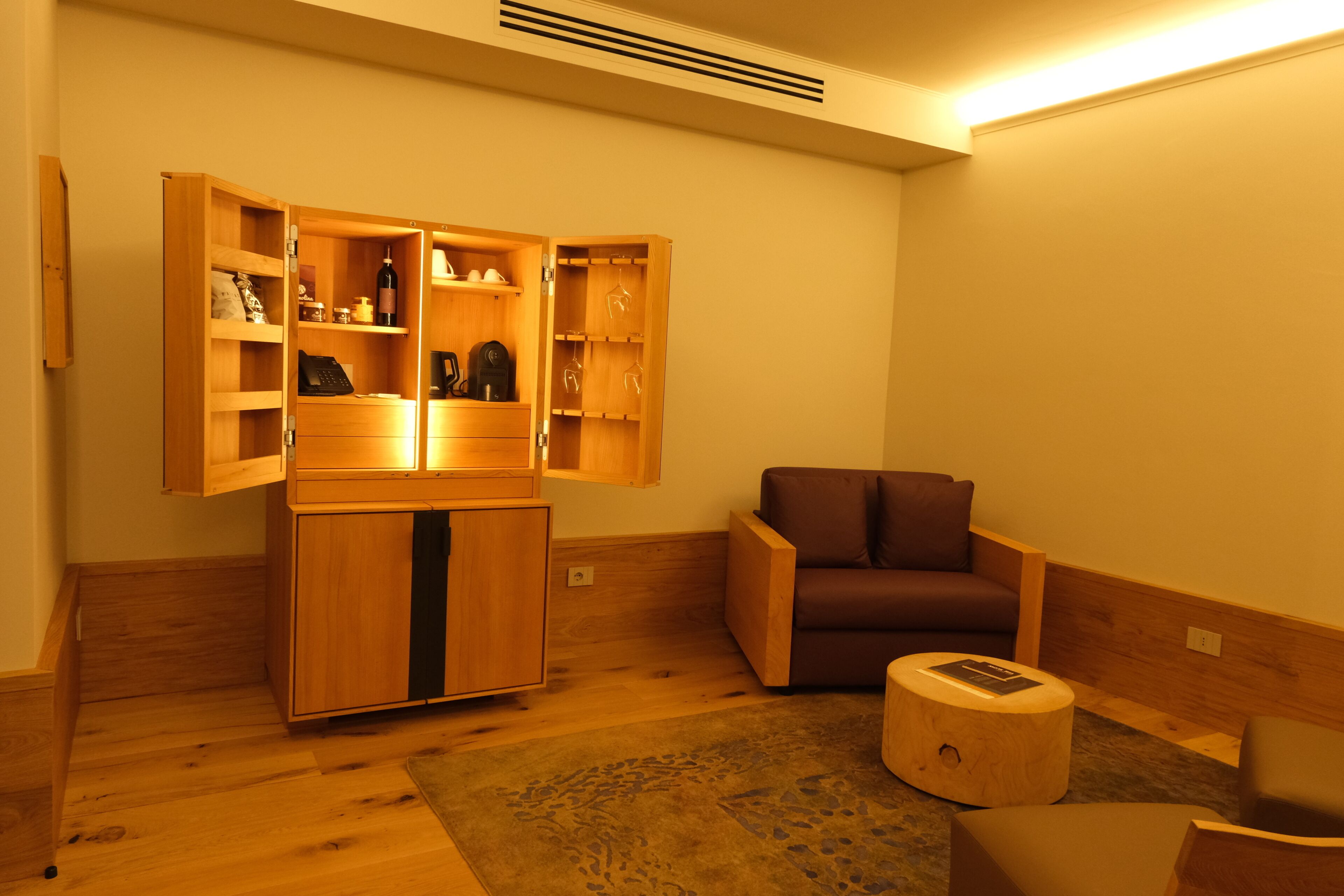 A room with a wooden cabinet, a brown armchair, and a small stool.