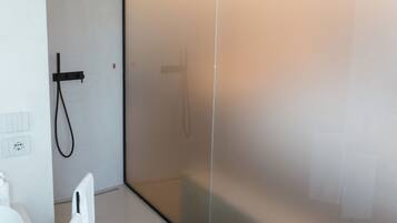 A modern bathroom with a white sink, a towel rack, and a glass shower enclosure.