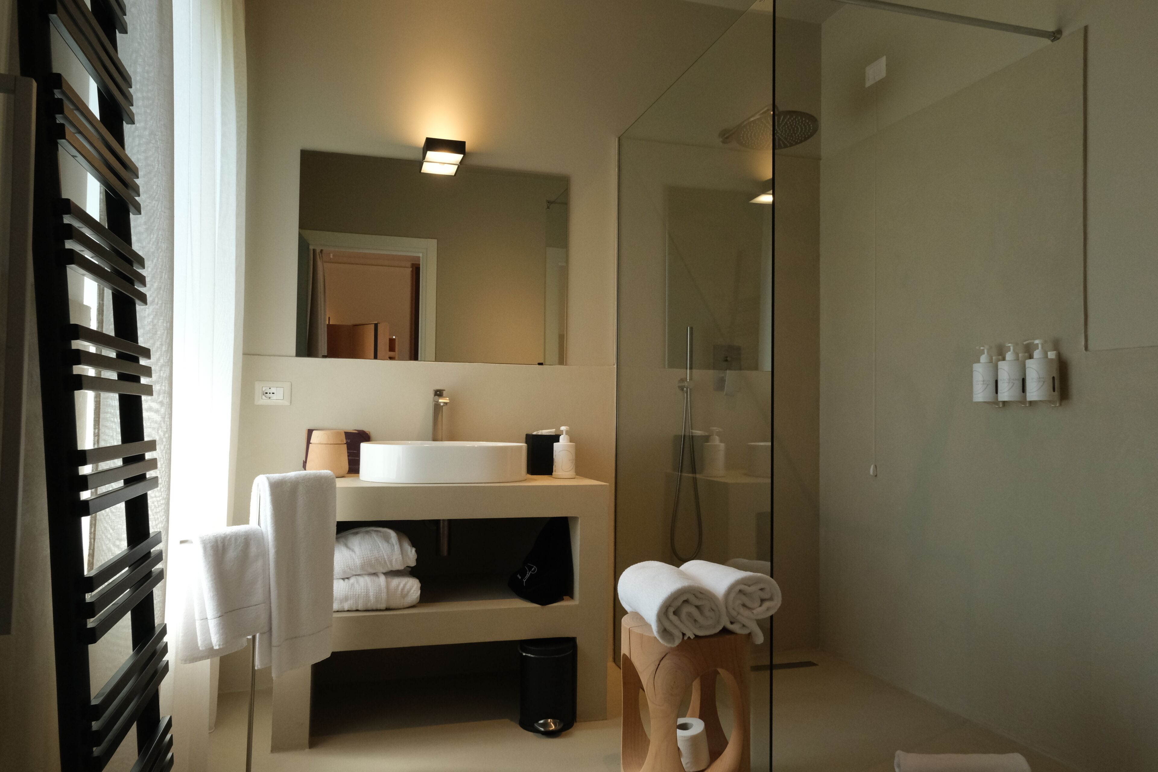 Ein modernes Badezimmer mit Glasdusche, Waschbecken mit Spiegel darüber und Handtuchhalter mit Handtüchern.
