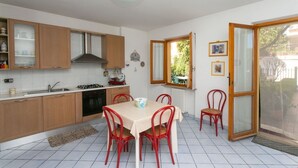 A kitchen with wooden cabinets, a gas stove, and a dining table with red chairs. - N043 - Numana, two-room apartment with garden (Sirolo)