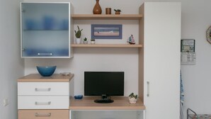 A modern room with a desk, a computer, a cabinet with a glass door, and shelves with decorative items. - N043 - Numana, two-room apartment with garden (Sirolo)