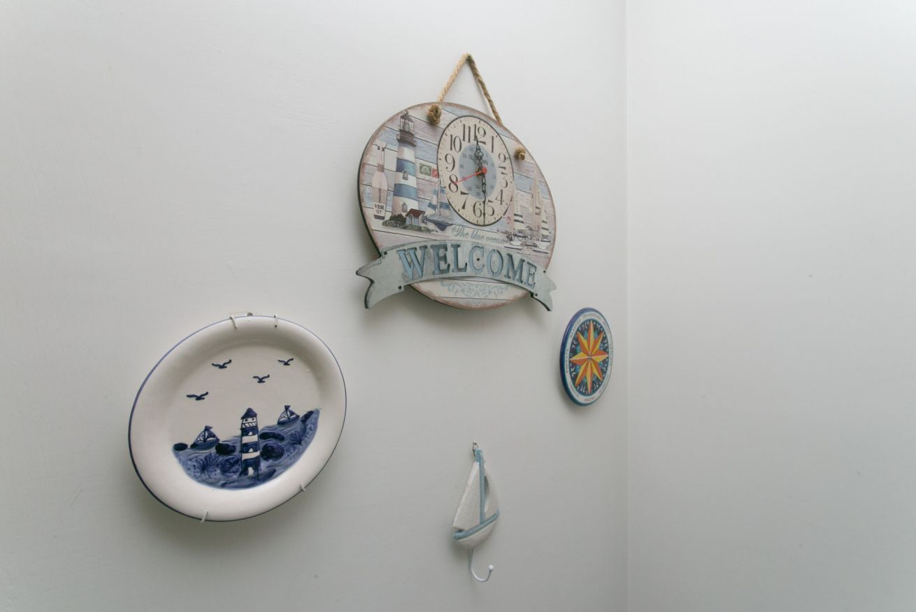 A wall with a welcome sign, a decorative plate, and a small hanging ornament.