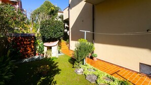 A residential courtyard with a small garden, a tiled patio, and a staircase leading to an upper level. - N043 - Numana, two-room apartment with garden (Sirolo)