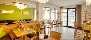 Un restaurante con cabinas y mesas, ventanas amplias y una pared verde.