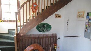 A staircase with a wooden handrail, a decorative wall sign, a small wooden arch, and a bulletin board with various items pinned to it. - Rennsteighotel Grüner Baum (Suhl)