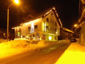Una calle cubierta de nieve con un edificio que muestra un cartel con la leyenda "Grüner Baum".