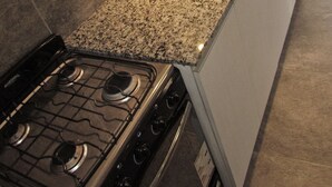 Uma cozinha com bancadas de granito, pia de aço inoxidável e fogão a gás.