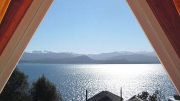 A triangular window with a view of a lake and mountains.