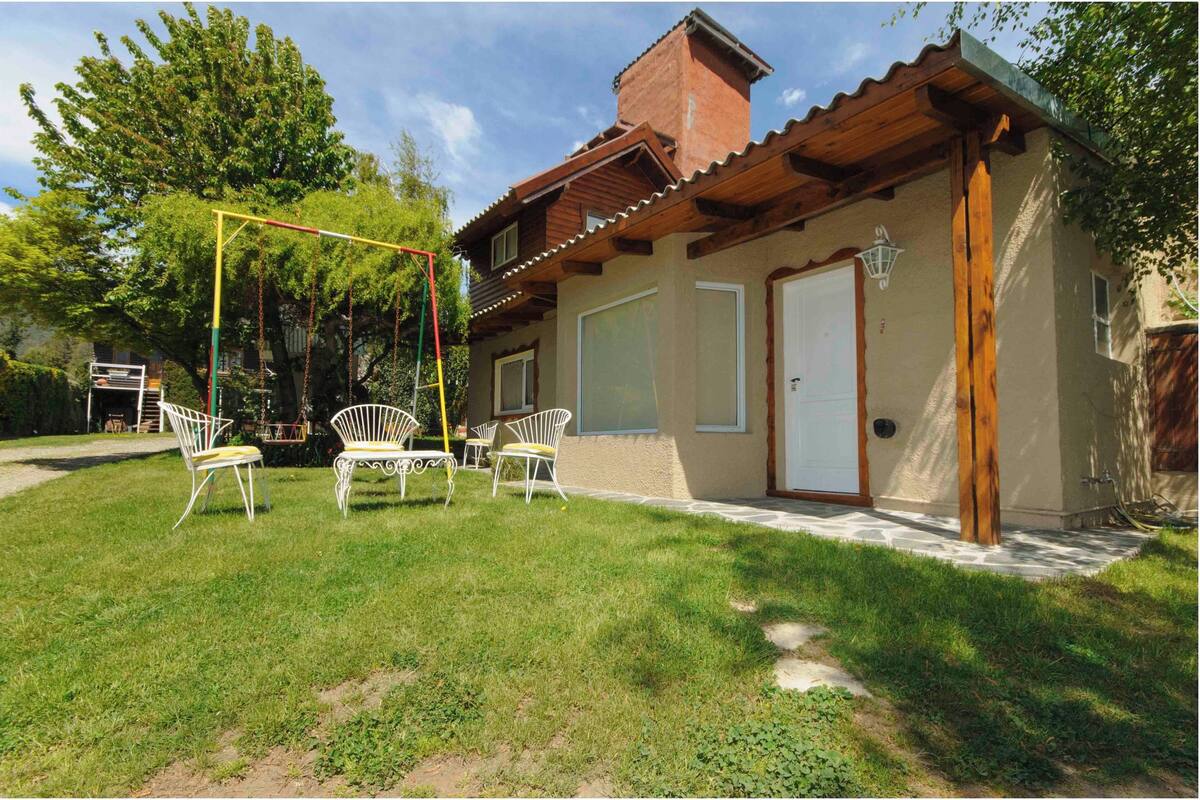 Una casa con un patio, un columpio y muebles de exterior.