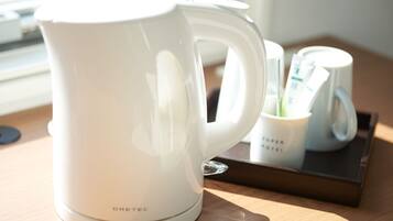 Ein weißes Wasserkocher auf einer Ablage mit einer Tasse und einem Löffelhalter.