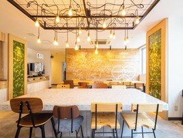 Un café moderno con una isla central, sillas de madera y una pared decorada con un mural de temática natural.