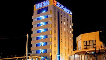 A multi-story hotel with illuminated signage, balconies, and a visible elevator shaft.