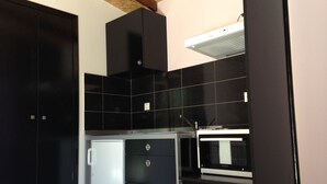 A modern kitchen with black cabinets, a built-in microwave, and a glass-fronted refrigerator. - Alex's Studio (Heraklion)