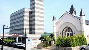 Un hotel moderno con un edificio alto y un edificio tradicional con techo a dos aguas.