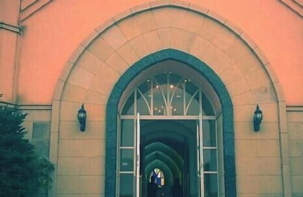 A building entrance with a large arched doorway, a glass panel, and two wall-mounted lanterns. - Miyoshi Grand Hotel (Miyoshi)