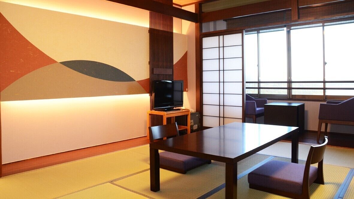 A traditional Japanese room with tatami flooring, a low table, and a television on a wooden stand.