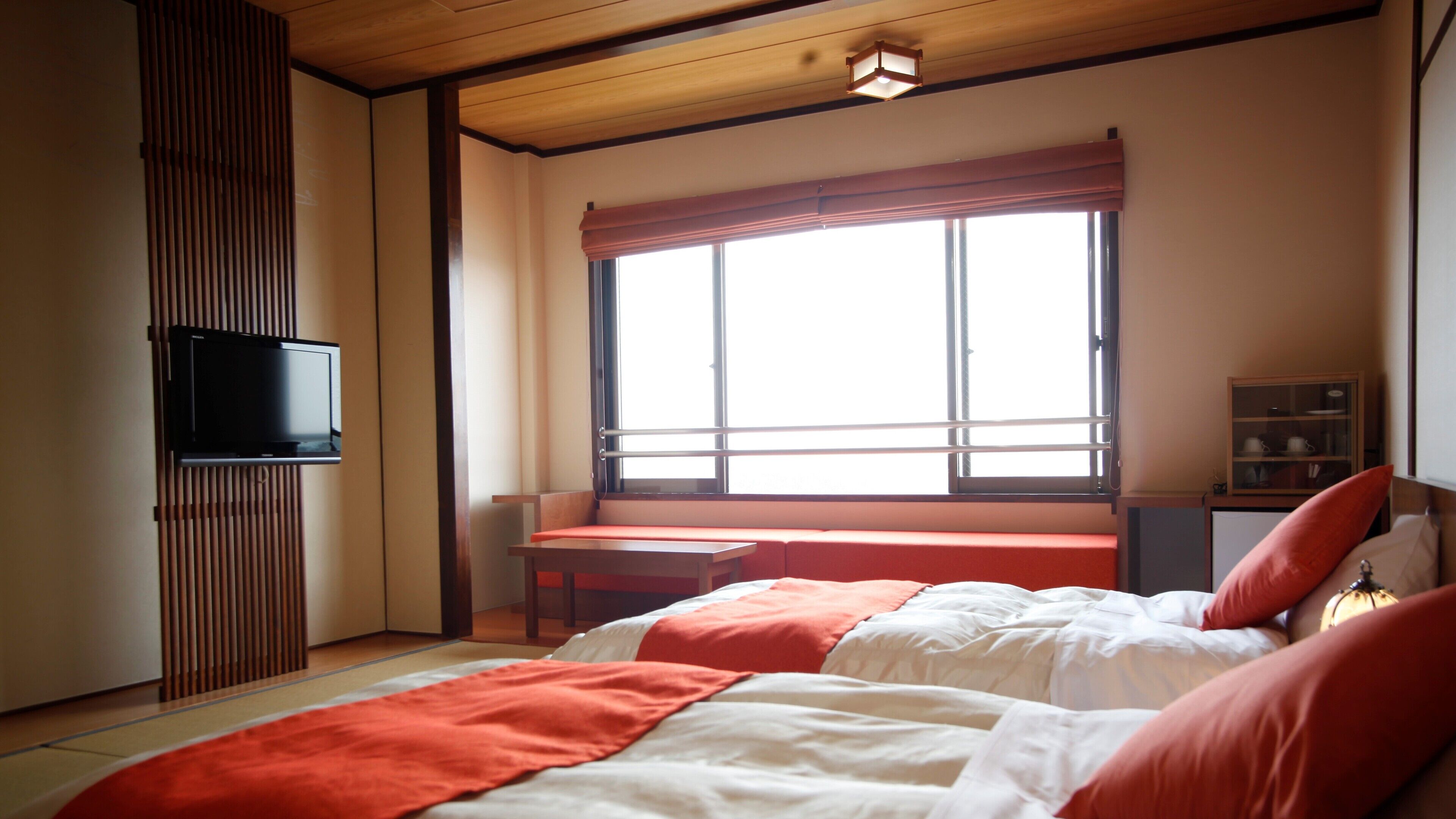 A bedroom with a bed, a TV, a window with a view, and a desk.