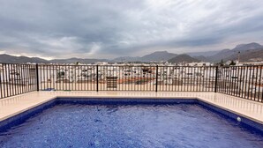 A rooftop pool with a view of distant mountains and buildings.