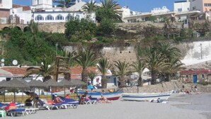 A coastal town with a beach, boats, and buildings including a church with a bell tower.