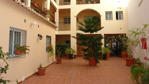 A courtyard with multiple balconies, potted plants, and a tiled floor.